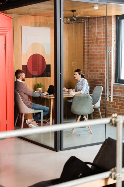 Selective focus of businesswoman holding paper cup and looking at businessman — Stock Photo