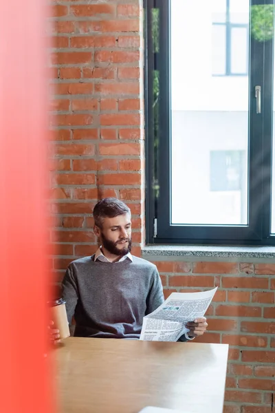 Enfoque selectivo de hombre de negocios guapo sosteniendo café para ir y leer el periódico - foto de stock