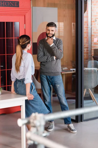 Selektiver Fokus eines bärtigen Mannes, der lächelt, während er die Frau im Amt ansieht — Stockfoto