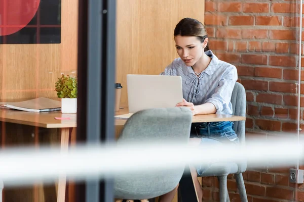 Селективная направленность деловой женщины на использование ноутбука в современном офисе — стоковое фото