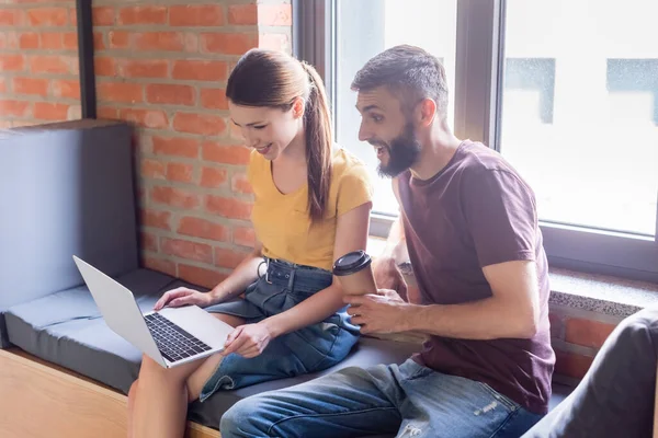 Glückliche Geschäftsfrau mit Laptop in der Nähe schöner Geschäftsmann hält Pappbecher — Stockfoto