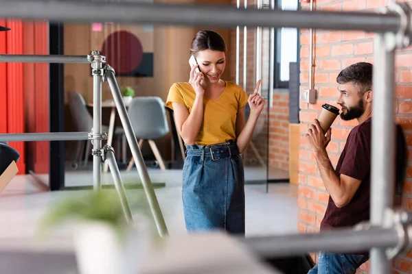 Selektiver Fokus der Geschäftsfrau, die mit dem Finger zeigt, während Geschäftsmann Pappbecher in der Hand hält — Stockfoto