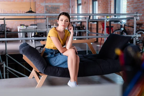 Selective focus of attractive businesswoman sitting on sofa in modern office — Stock Photo