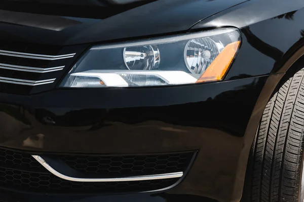 Headlight of black car with sunlight outdoors — Stock Photo