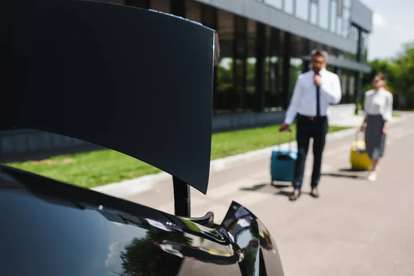 Selektiver Fokus von Geschäftsleuten mit Koffern, die auf der Stadtstraße zum Auto laufen — Stockfoto