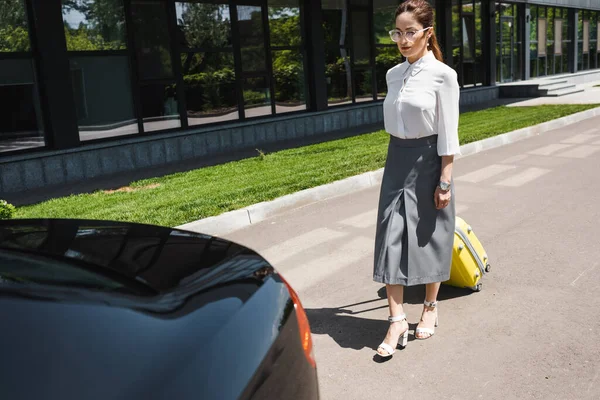 Geschäftsfrau läuft mit Gepäck zum Auto auf Stadtstraße — Stockfoto
