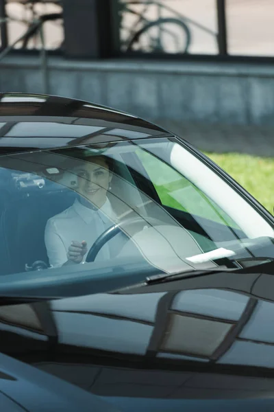 Приваблива бізнес-леді сидить в машині і посміхається на камеру — стокове фото