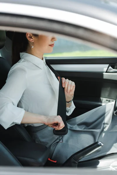 Vue recadrée de la femme d'affaires tenant la ceinture de sécurité tout en étant assis en auto — Photo de stock