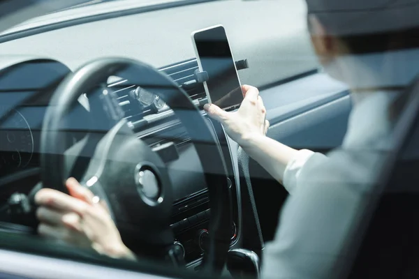 Concentration sélective de la femme d'affaires tenant smartphone tout en conduisant une voiture — Photo de stock