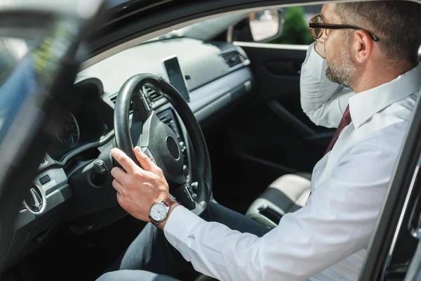 Selective focus of businessman sitting on driver seat in car with open door — Stock Photo