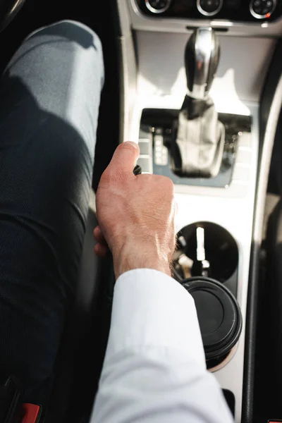Cropped view of businessman driving car near disposable cup in cup holder — Stock Photo