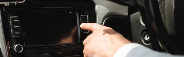 Imagen panorámica del hombre de negocios utilizando el sistema de audio del vehículo en el coche - foto de stock
