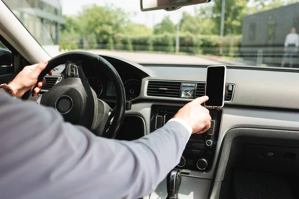 Vista recortada del hombre de negocios utilizando el teléfono inteligente mientras conduce auto - foto de stock