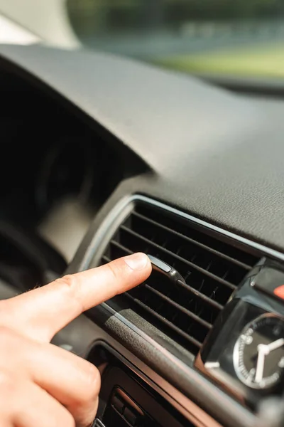 Ausgeschnittene Ansicht eines Mannes, der Lüftungsanlage im Auto justiert — Stockfoto