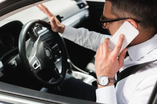 Enfoque selectivo del hombre de negocios que habla en el teléfono inteligente mientras conduce el coche - foto de stock