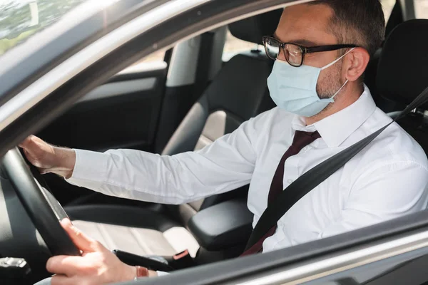 Enfoque selectivo del hombre de negocios en la máscara médica coche de conducción - foto de stock