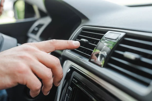 Cropped view of man adjusting air conditioner on dashboard in auto — Stock Photo