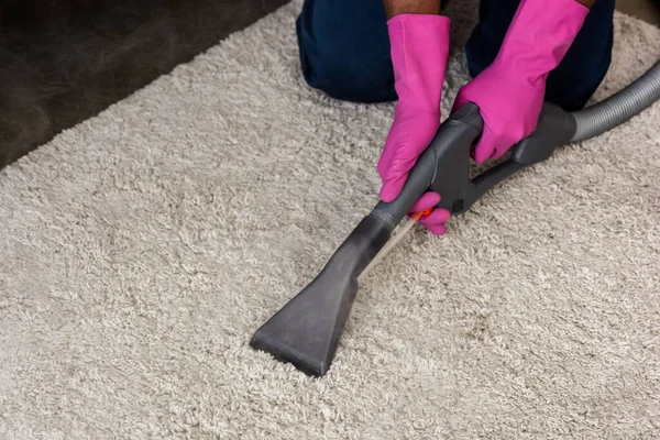 Vista cortada do limpador americano africano usando aspirador de pó enquanto limpa o tapete em casa — Fotografia de Stock