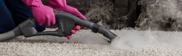 Coltivazione panoramica di detergente in guanti di gomma utilizzando aspirapolvere con vapore caldo su moquette — Foto stock