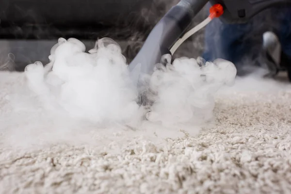 Foco seletivo de aspirador de pó com vapor quente no tapete em casa — Fotografia de Stock
