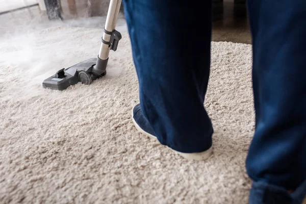 Cropped view of cleaner using vacuum cleaner with hot steam on carpet in living room — Stock Photo