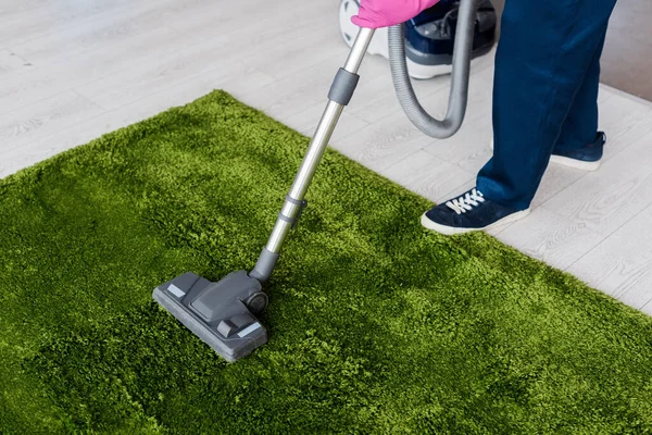 Vue recadrée du nettoyeur à l'aide d'un aspirateur sur tapis vert — Photo de stock