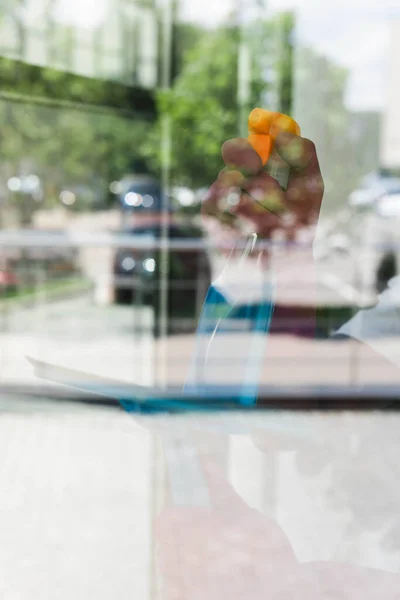 Selective focus of cleaner using detergent and squeegee handle while cleaning glass of window — Stock Photo