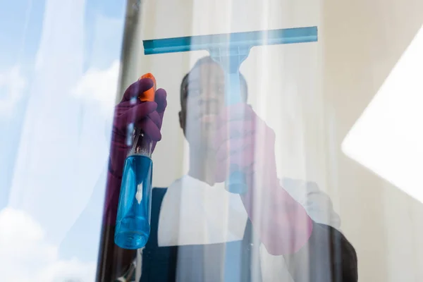 Selective focus of african american worker of cleaning service cleaning glass of window — Stock Photo