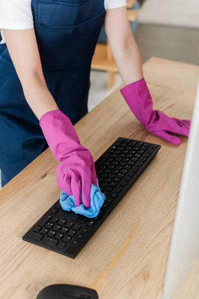 Vue recadrée du travailleur du service de nettoyage nettoyage clavier d'ordinateur avec chiffon sur la table — Photo de stock