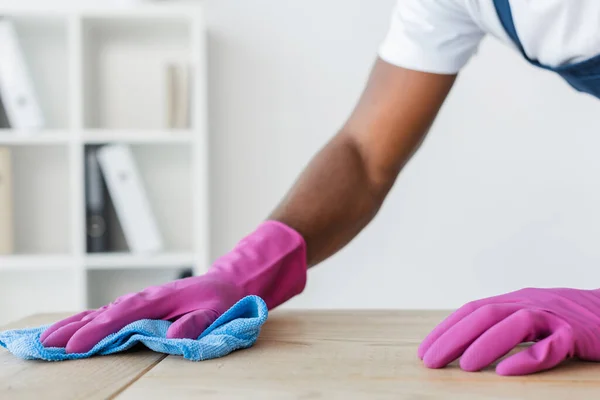 Vista ritagliata del lavoratore africano americano del servizio di pulizia pulizia tavolo ufficio — Foto stock