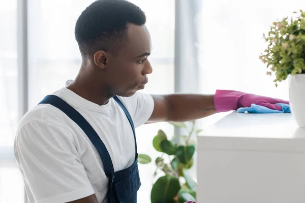 Selective focus of african american worker of office cleaning service cleaning cupboard with rag — Stock Photo