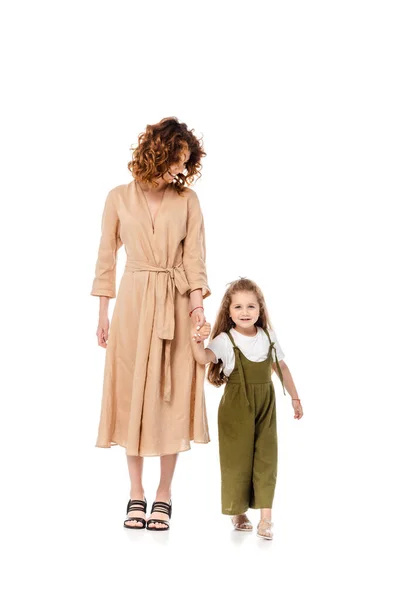 Madre rizada e hija feliz cogidas de la mano aisladas en blanco - foto de stock