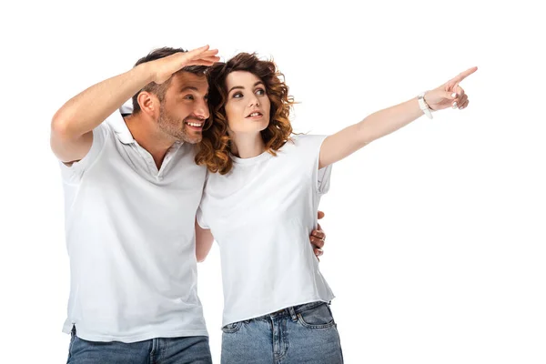 Mujer rizada señalando con el dedo cerca de hombre alegre mirando hacia otro lado aislado en blanco - foto de stock