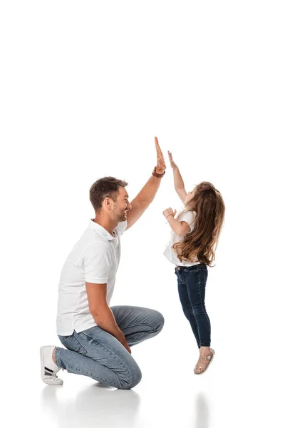 Mignon enfant sautant tout en donnant haute cinq à père heureux sur blanc — Photo de stock