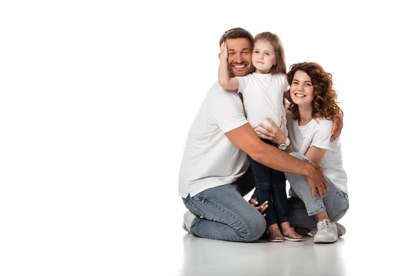 Glückliches Kind umarmt Vater neben fröhlicher Mutter auf Weiß — Stockfoto