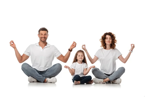 Feliz familia sentada en yoga pose sobre blanco - foto de stock