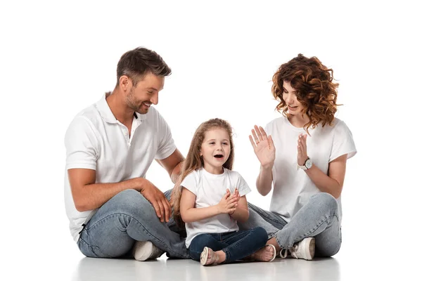 Glücklicher Vater und Mutter, die die süße Tochter beim Händeklatschen auf Weiß betrachten — Stockfoto