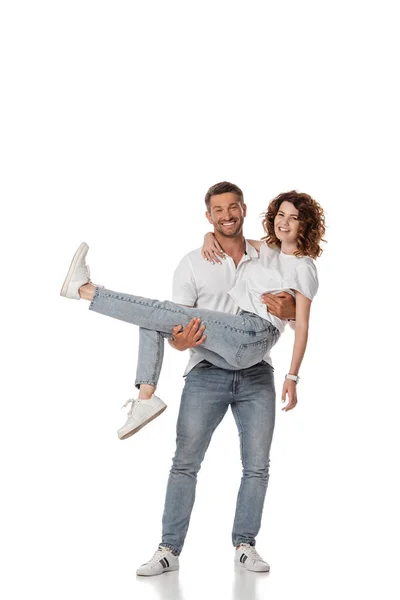 Feliz hombre sosteniendo en brazos rizado esposa en blanco - foto de stock