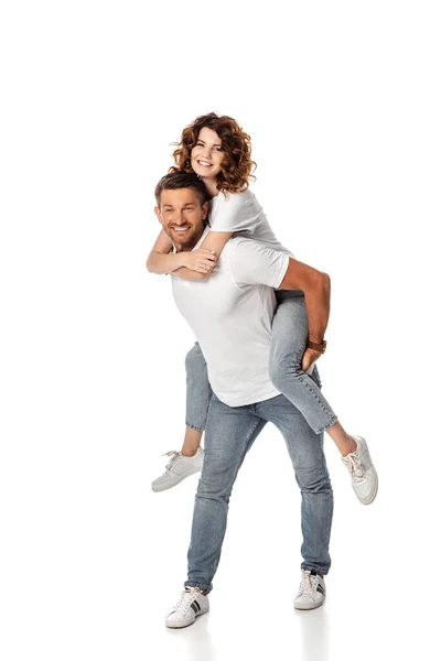 Cheerful man piggybacking curly and happy wife on white — Stock Photo