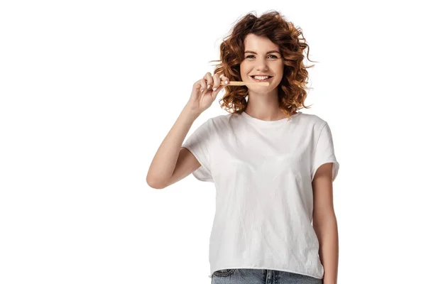 Cheerful and curly woman brushing teeth isolated on white — Stock Photo