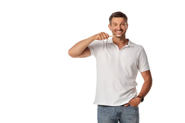 Hombre alegre sosteniendo el cepillo de dientes y de pie con la mano en el bolsillo aislado en blanco — Stock Photo