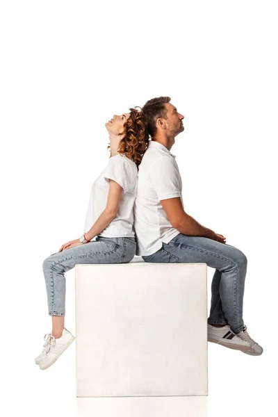 Side view of couple sitting on cube and looking up on white — Stock Photo
