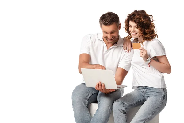 Щаслива жінка тримає кредитну картку біля чоловіка за допомогою ноутбука ізольовано на білому — стокове фото