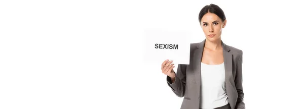 Cultivo panorámico de atractiva mujer de negocios con pancarta con letras de sexismo aislado en blanco - foto de stock