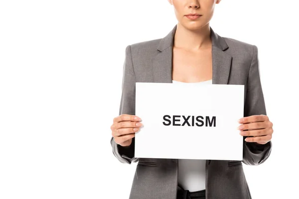 Vista recortada de la empresaria sosteniendo pancarta con letras de sexismo aislado en blanco - foto de stock