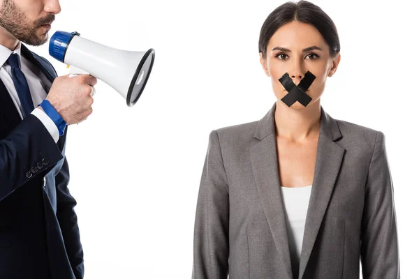 Bearded businessman holding megaphone near businesswoman with duct tape on mouth isolated on white, gender inequality concept — Stock Photo