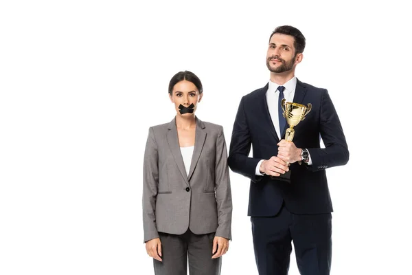 Businessman holding trophy near businesswoman with duct tape on mouth isolated on white, gender inequality concept — Stock Photo