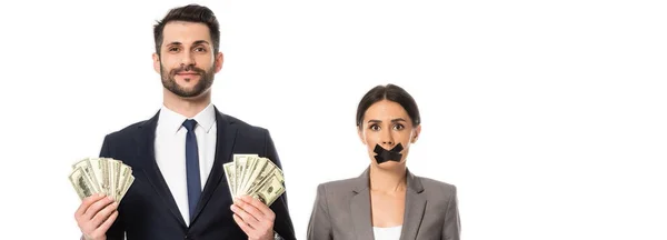 Горизонтальне зображення бізнесмена, що тримає долари біля бізнес-леді зі стрічкою в роті ізольовано на білому — стокове фото