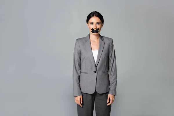 Бізнес-леді з скотчем на роті стоячи ізольовані на сірому — стокове фото