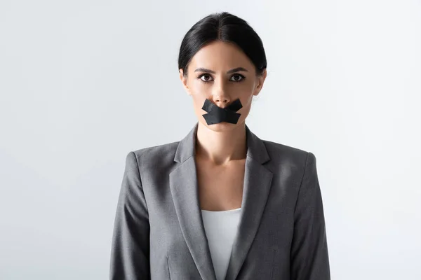 Businesswoman with scotch tape on mouth standing isolated on white — Stock Photo